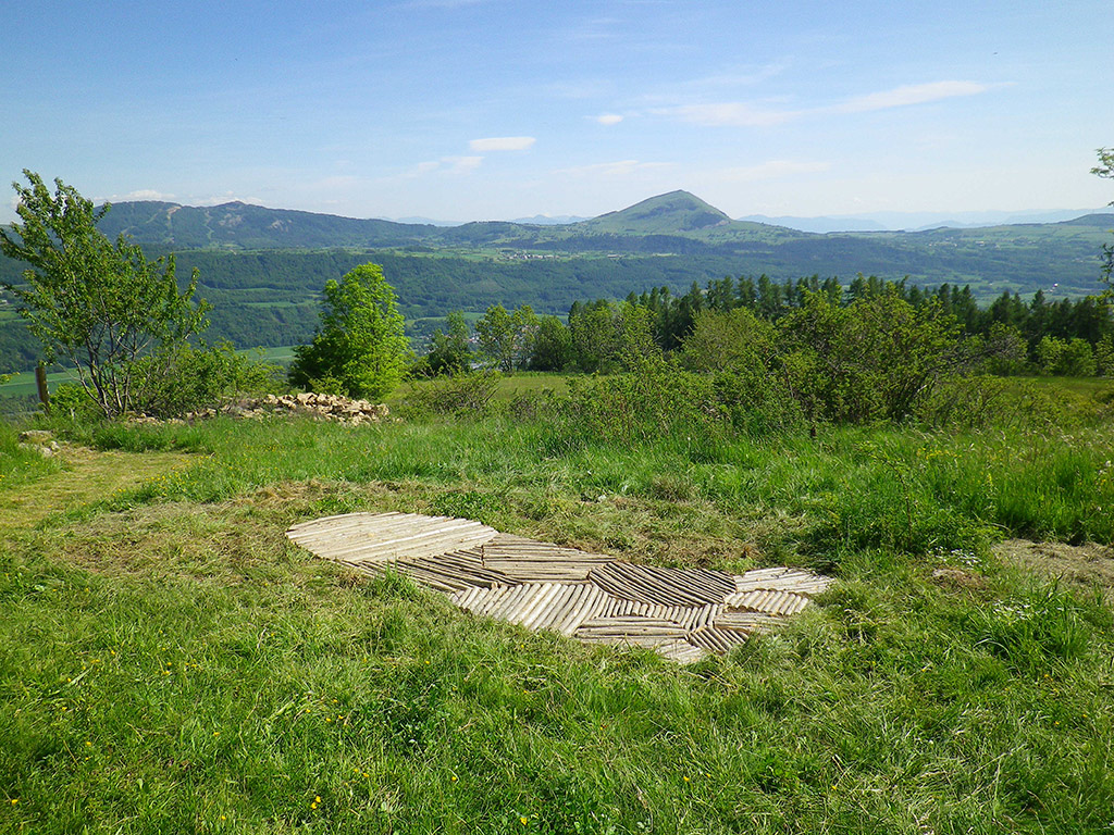 Installation dans la campagne faite de bois créant une trace géante laissée au sol.