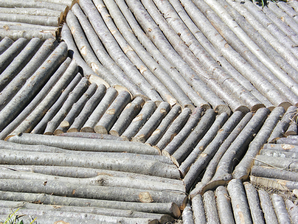 Installation dans la campagne faite de bois créant une trace géante laissée au sol.  