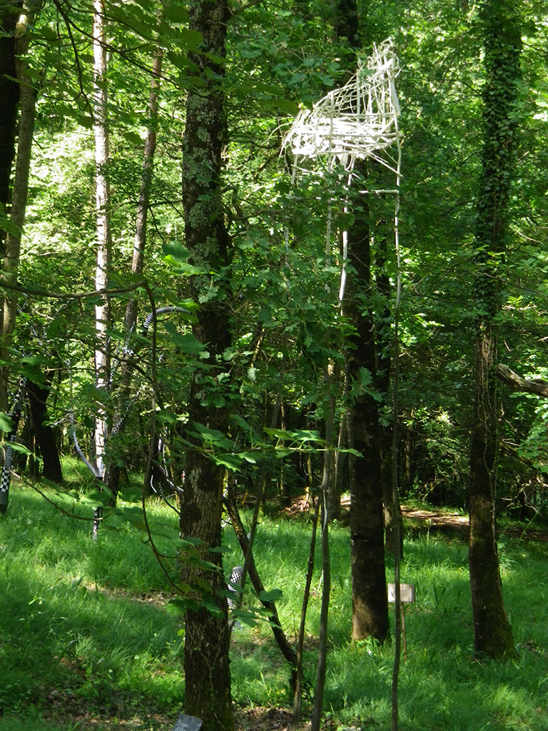 Dans les bois, une installation en hauteur faite de branchages et de plumes.