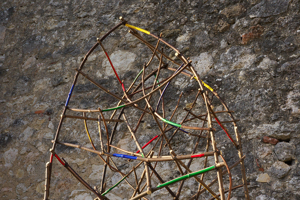 Détails de la sculpture de l'artiste Anne Mangeot, structure tressée en bois avec des parties colorées.