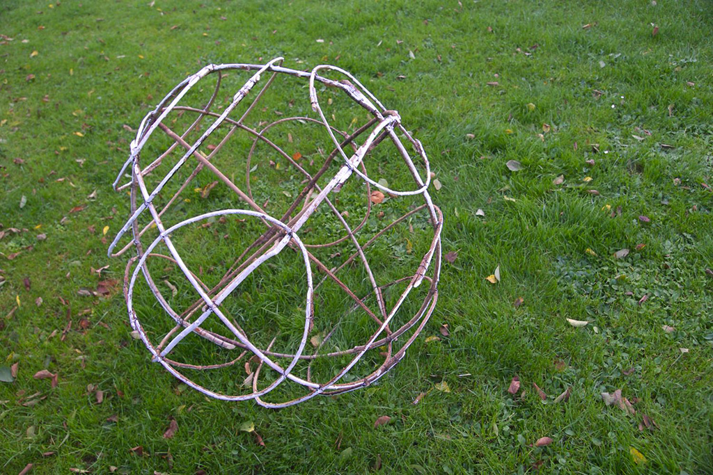 Structures de bois tressés formants de grandes boules dans un jardin.