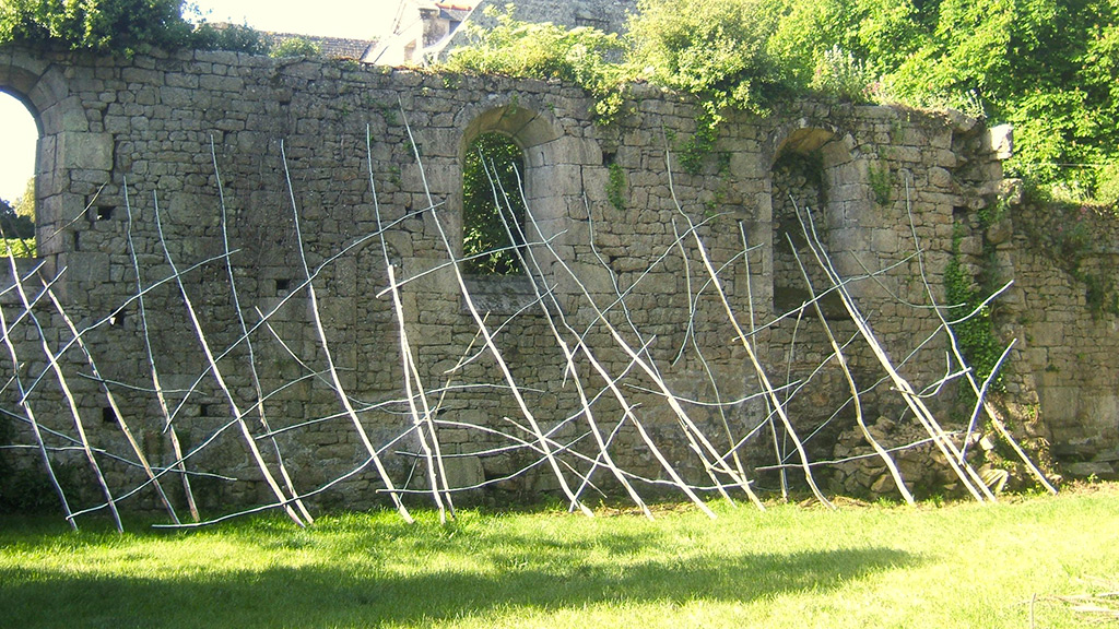 Grande installation in situ d'Anne Mangeot adossée à un vieux mur de pierre.