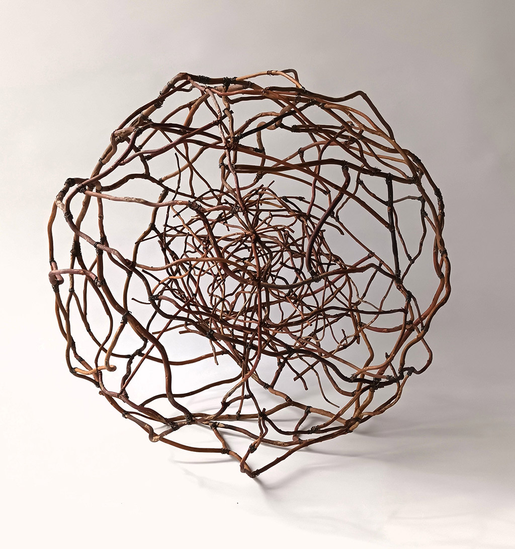 Sculpture d'Anne Mangeot formant une grande sphère avec en son coeur une plus petite sphère plus dense, le tout réalisé en branche de saule tortueux.