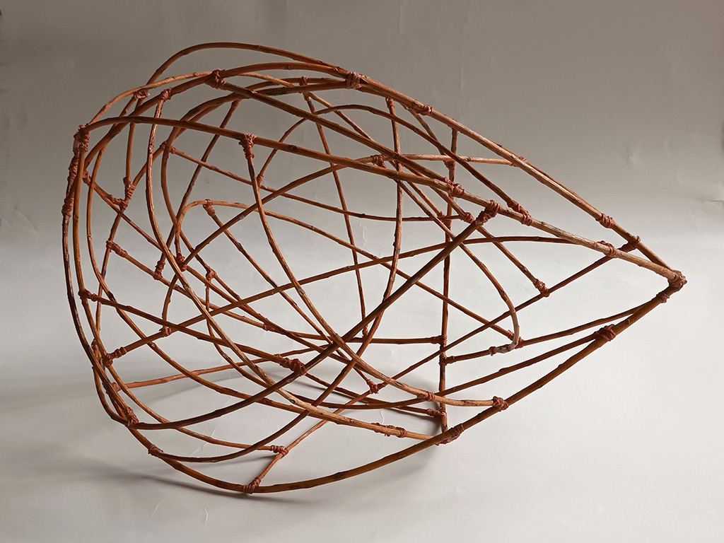 Sculpture d'Anne Mangeot en forme de goutte à l'horizontale, ajourée et réalisée à base de branches.