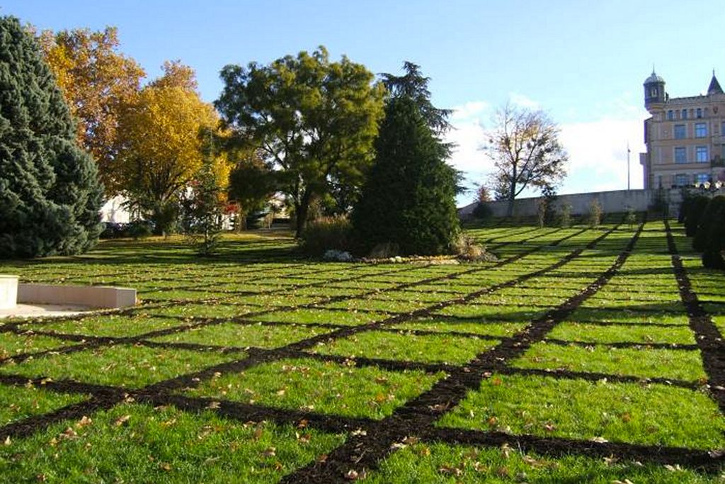 Installation d’art contemporain par l'artiste Anne Mangeot en extérieur: dans la cour d'un château, un quadrillage sur des centaines de mètres carrés a été créé sur la pelouse grâce a de la terre déposée en lignes droites.