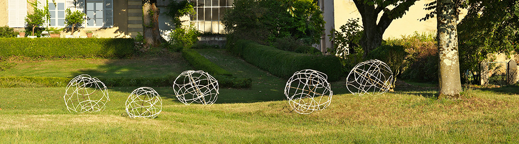 Photo de nuit d'une installation de l'artiste Anne Mangeot dans le parc de l'hôtel de Nayme. On y voit quatre grandes sphéres vides faites de branchages.